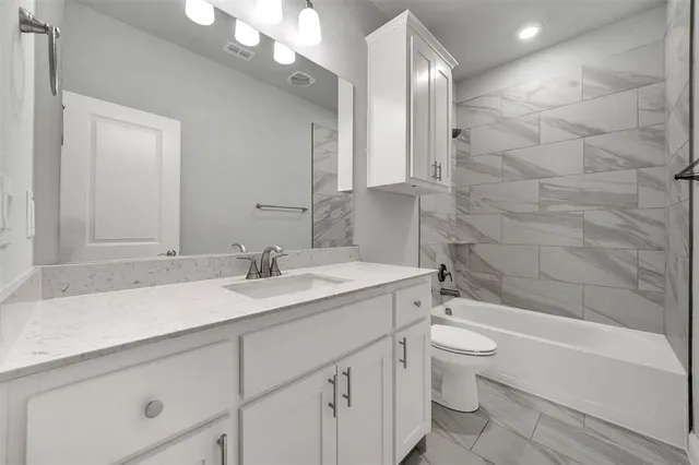 a bathroom with a granite countertop sink a toilet and bathtub