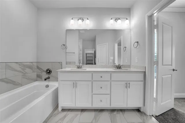 a bathroom with a bathtub a double vanity sink and a mirror