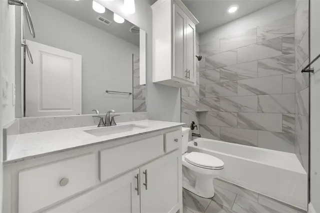 a bathroom with a granite countertop sink toilet a mirror and bathtub