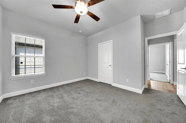 an empty room with chandelier fan and windows