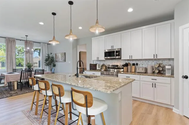 a kitchen with stainless steel appliances granite countertop a stove a sink a microwave a dining table and chairs