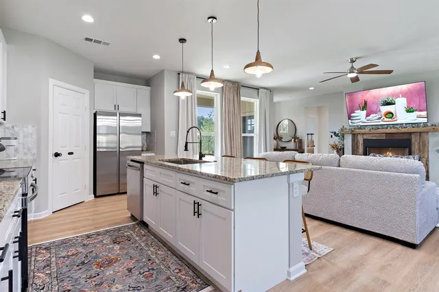 a large kitchen with stainless steel appliances granite countertop a stove a sink a refrigerator and a wooden cabinets