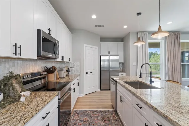 a kitchen with stainless steel appliances granite countertop a sink stove and refrigerator