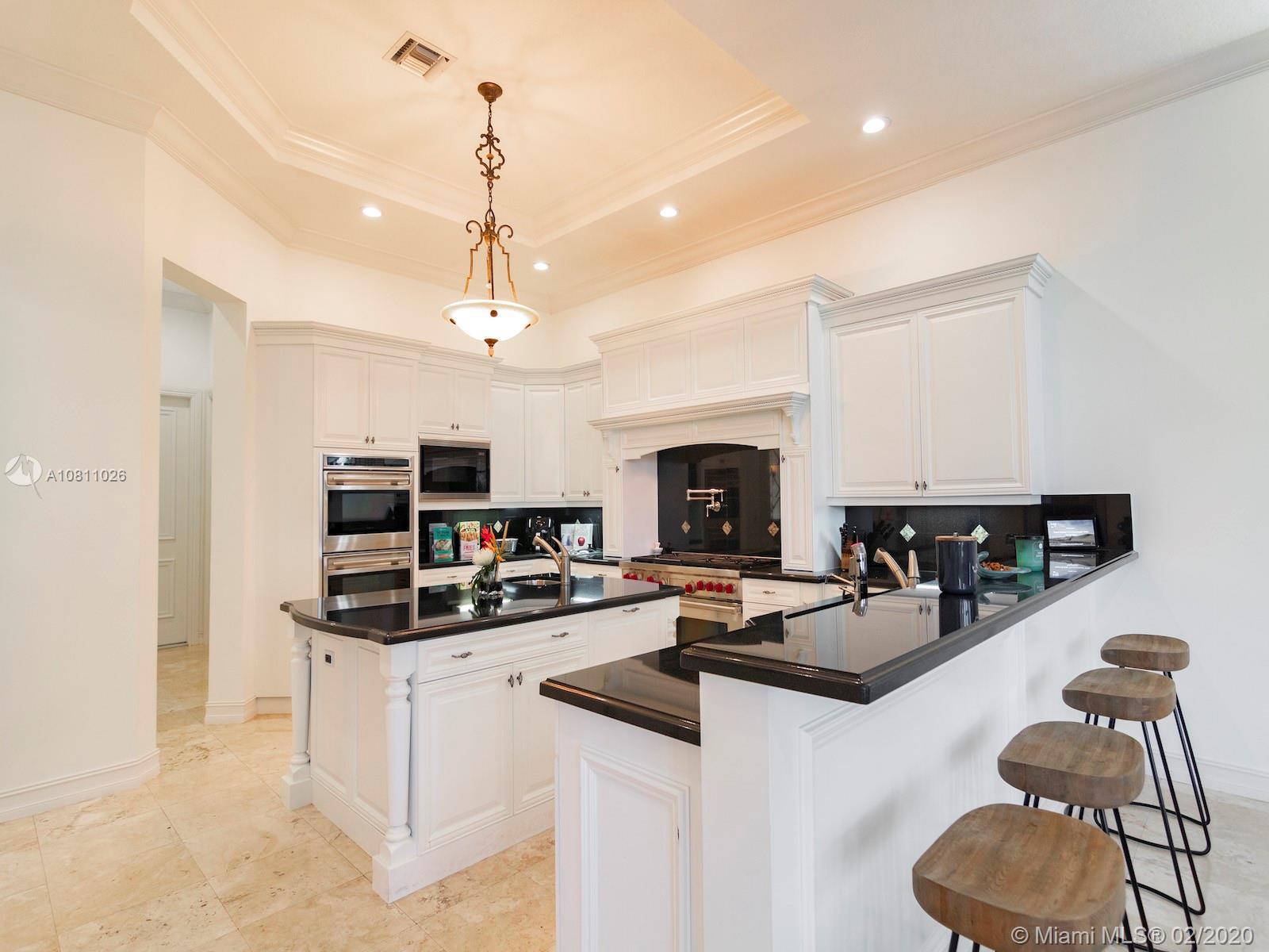 9597 Bridgebrook Drive Boca Raton, FL 33496 - Photo 15 of 37 a kitchen with kitchen island granite countertop a stove and a wooden floor