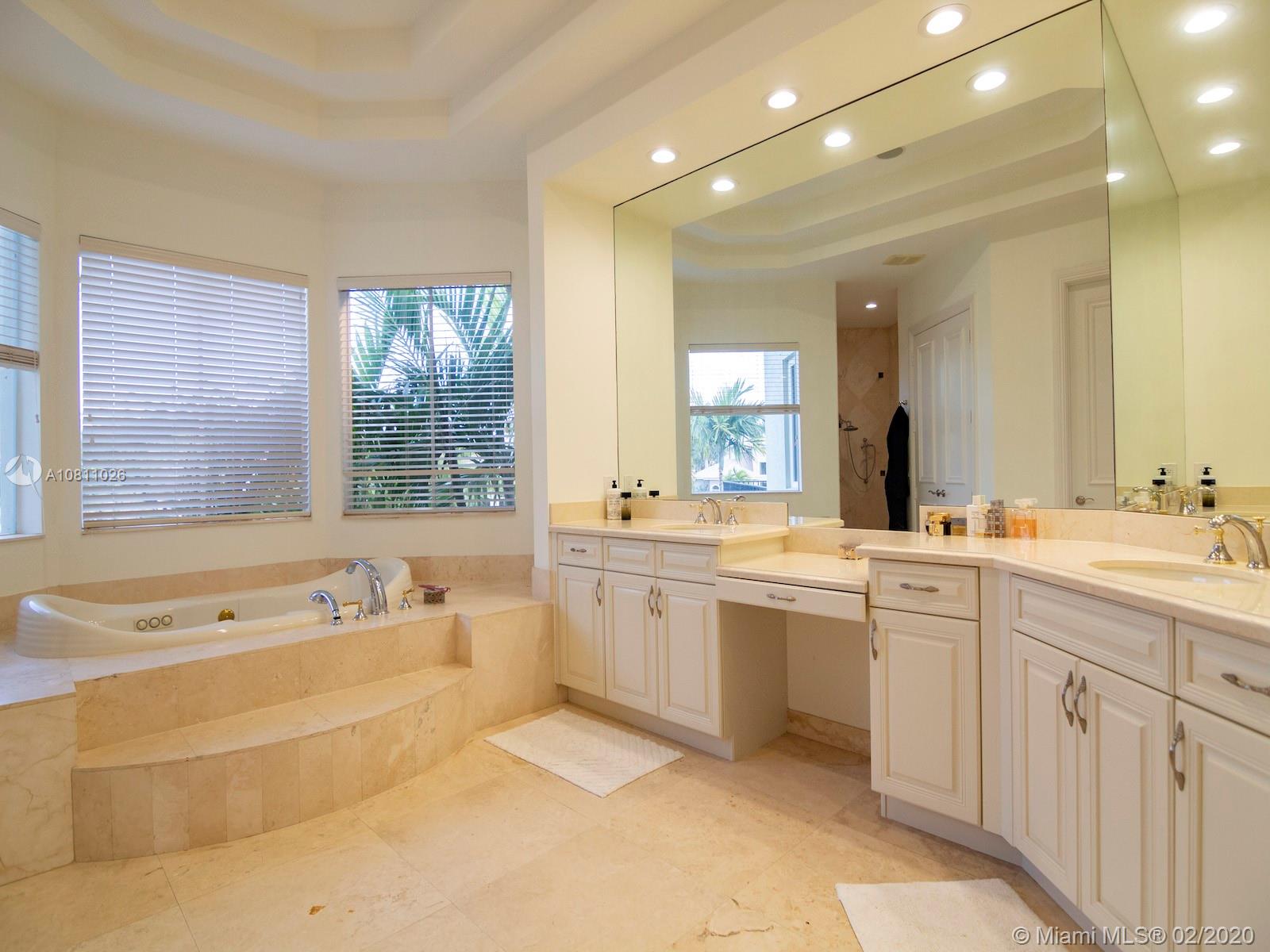 9597 Bridgebrook Drive Boca Raton, FL 33496 - Photo 19 of 37 a spacious bathroom with a sink a large mirror and a bathtub
