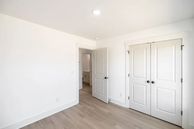 an empty room with wooden floor and closet area