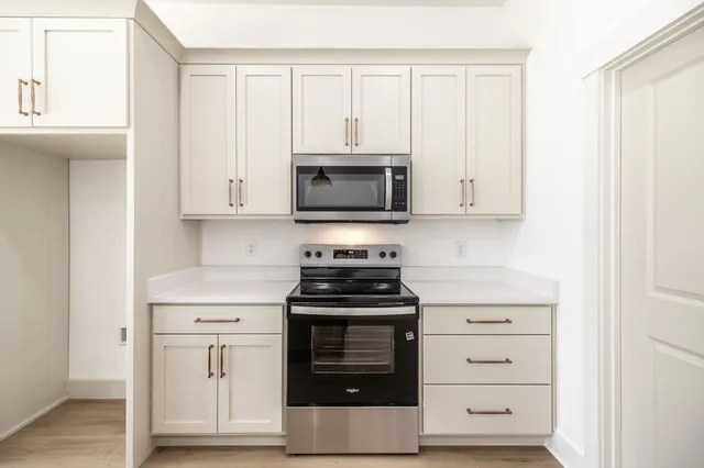 a kitchen with stainless steel appliances granite countertop white cabinets and a stove a oven with white countertops