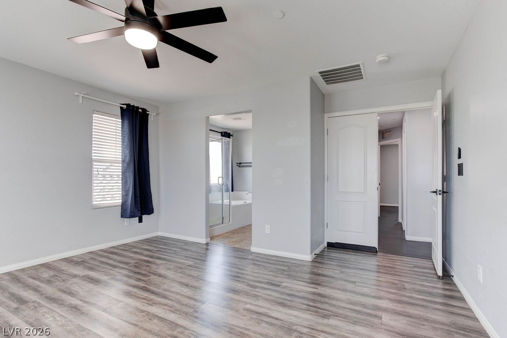 7724 Vibrant Thread Court Las Vegas, NV 89149 - Photo 21 of 43 A well-lit bedroom with durable plank flooring transitions seamlessly into an adjoining bathroom.