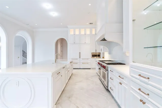 a large white kitchen with cabinets a sink a stove and a refrigerator