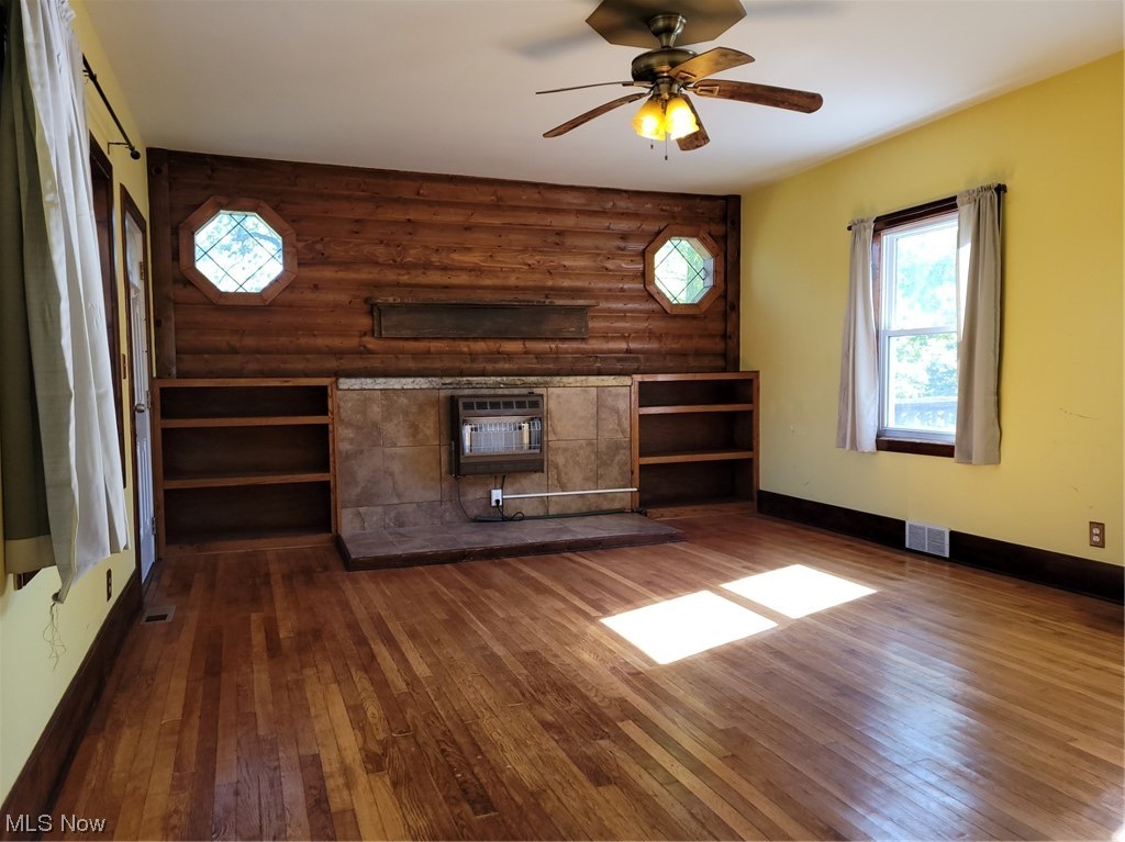 22922 Putney Ridge Road Quaker City, OH 43773 - Photo 17 of 31 Living room featuring dark hardwood flooring, log walls, a wall mounted air conditioner, and ceiling fan
