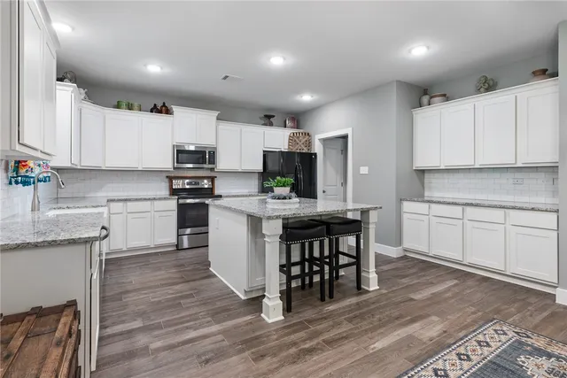 a kitchen with kitchen island granite countertop wooden floors and white cabinets