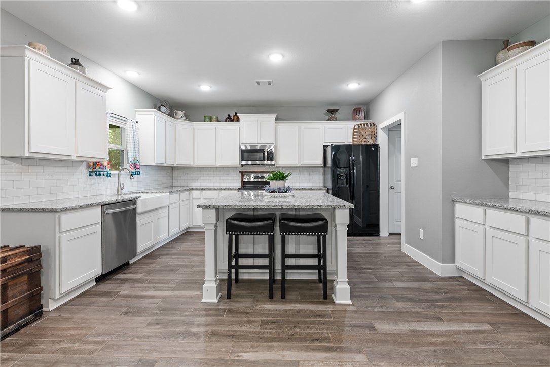 8729 Nathan Drive Waller, TX 77484 - Photo 13 of 48 Kitchen featuring appliances with stainless steel finishes, white cabinets, a kitchen bar, tasteful backsplash, and recessed lighting