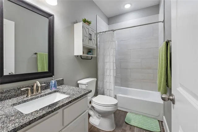 a bathroom with a granite countertop sink toilet and shower