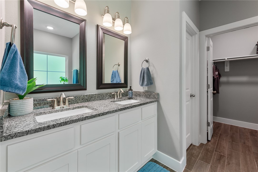 8729 Nathan Drive Waller, TX 77484 - Photo 30 of 48 Bathroom with double vanity, a walk in closet, and wood finished floors