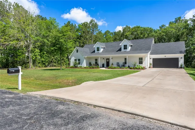 a view of a house with a big yard and large trees