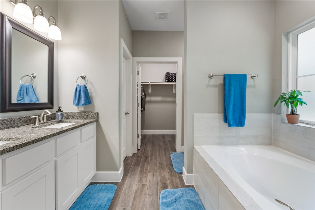 8729 Nathan Drive Waller, TX 77484 - Photo 31 of 48 Full bathroom featuring a bath, double vanity, wood finished floors, and a walk in closet