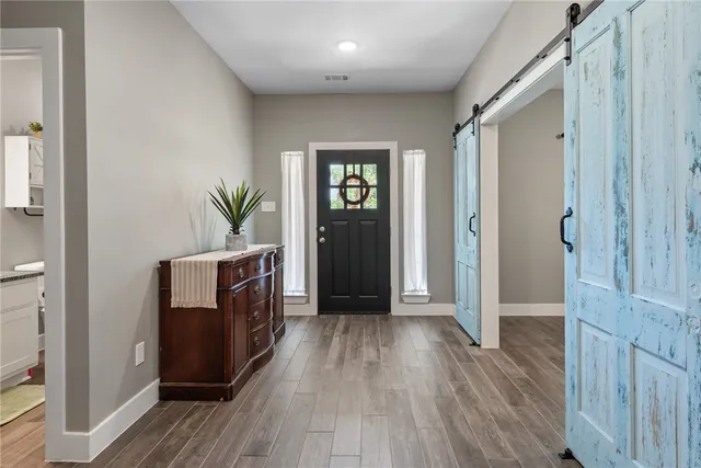 a view of hallway with window and wooden floor