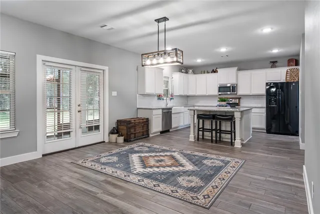 a open kitchen with stainless steel appliances granite countertop a stove top oven a sink dishwasher and a fireplace with wooden floor