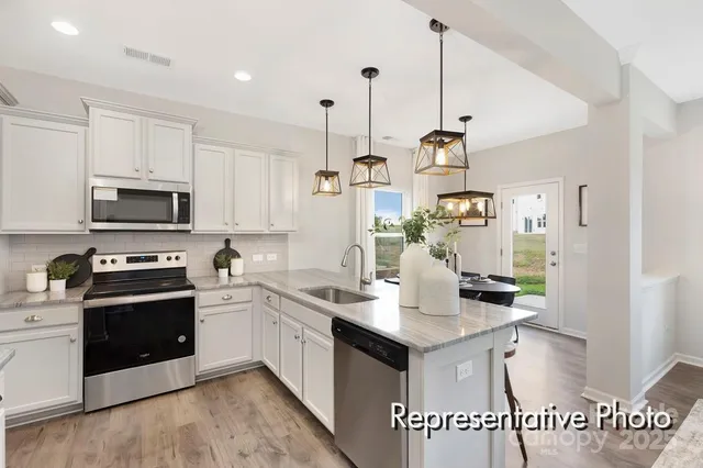 a kitchen with kitchen island granite countertop a sink cabinets and stainless steel appliances