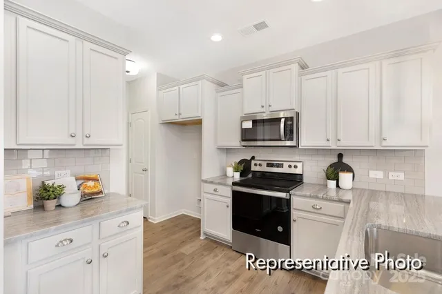 a kitchen with granite countertop white cabinets and stainless steel appliances