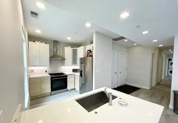 a kitchen with stainless steel appliances kitchen island sink refrigerator and cabinets