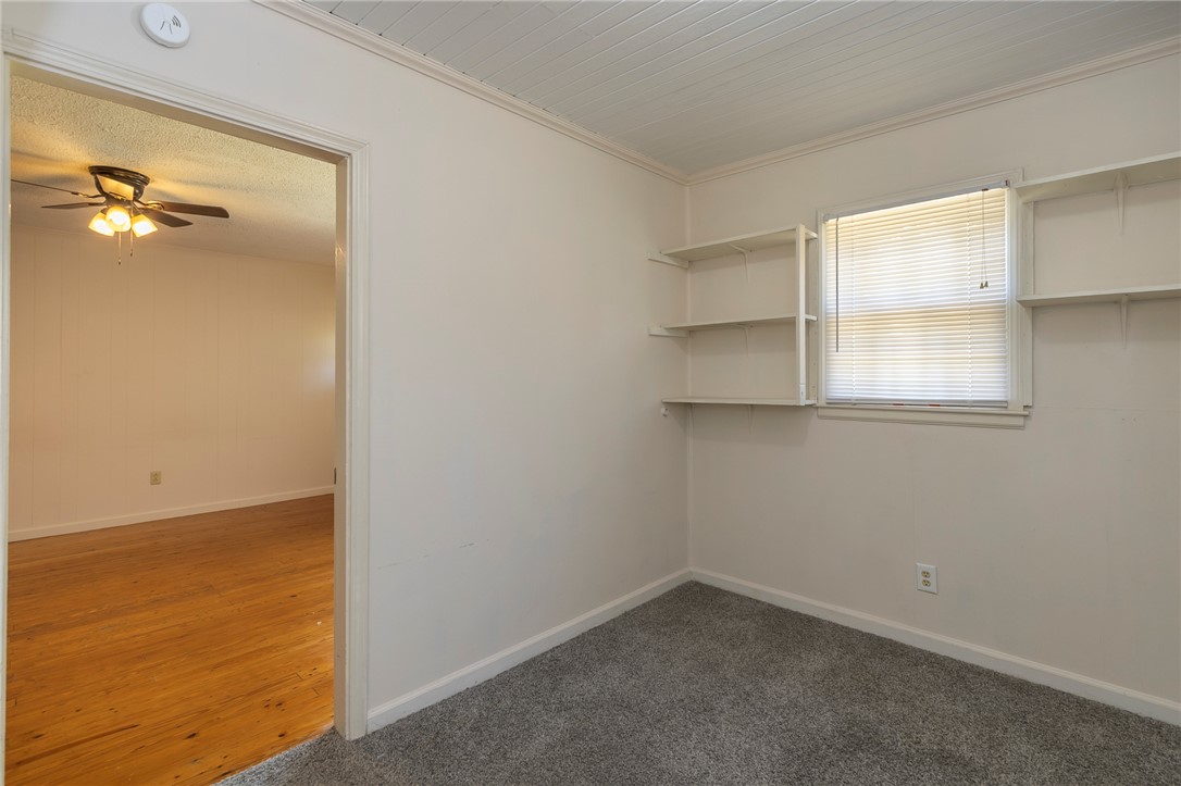 A quiet bedroom offers plush carpeting, built-in shelving, and a beadboard ceiling finish.