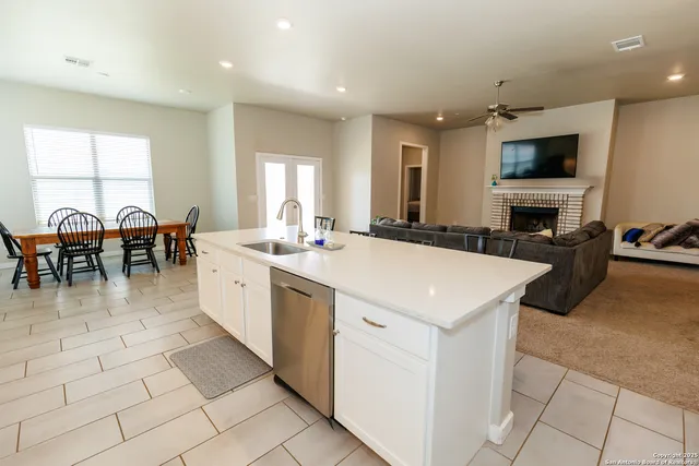 a large white kitchen with a sink and dining table chair