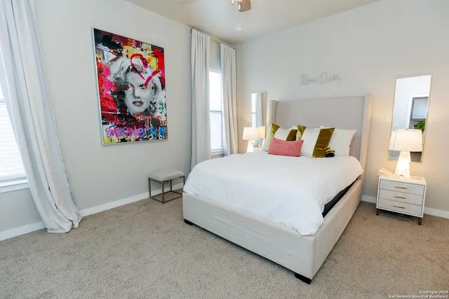 a spacious bedroom with a bed and painting on the wall