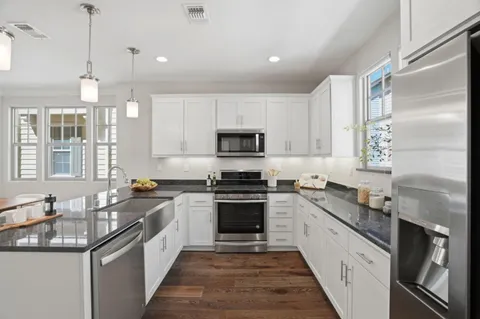 a kitchen with granite countertop stainless steel appliances a sink stove and cabinets