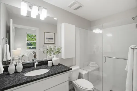 a bathroom with a granite countertop sink mirror and toilet