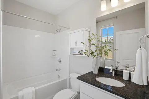 a bathroom with a granite countertop sink a toilet and shower