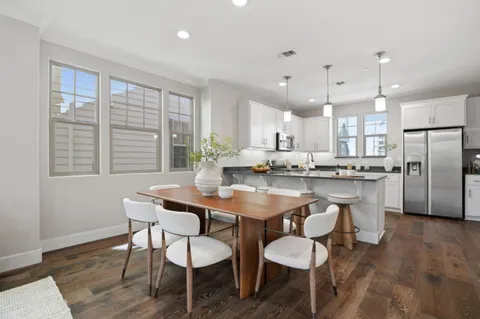 a kitchen with stainless steel appliances kitchen island granite countertop a dining table chairs and sink