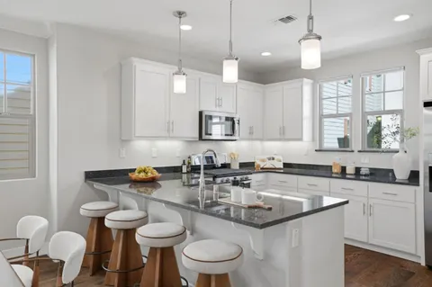 a kitchen with granite countertop a sink a stove a dining table and chairs