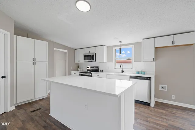 a kitchen with stainless steel appliances a sink a stove a refrigerator cabinets and a center island