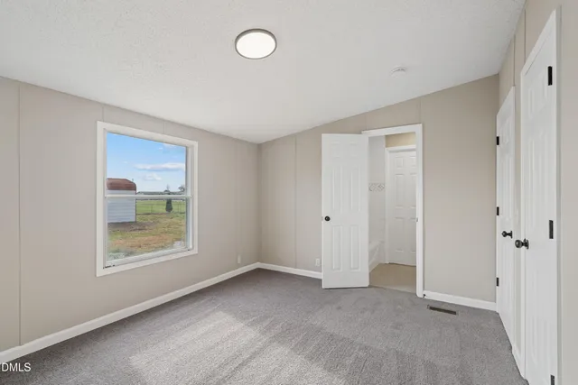 a view of an empty room with window and closet area