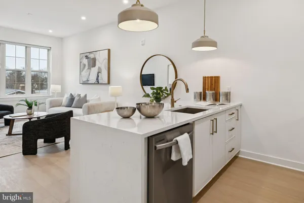 a kitchen with a sink dishwasher a dining table and chairs with wooden floor
