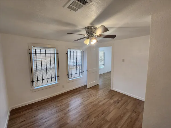 an empty room with wooden floor and windows