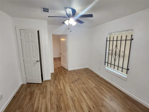 a view of empty room with wooden floor and fan