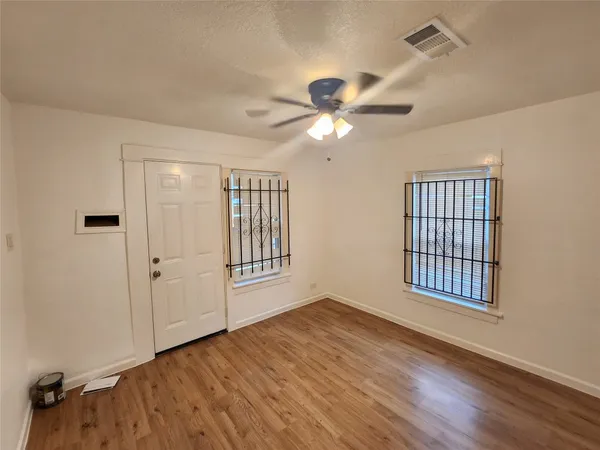 a view of an empty room with a window and wooden floor