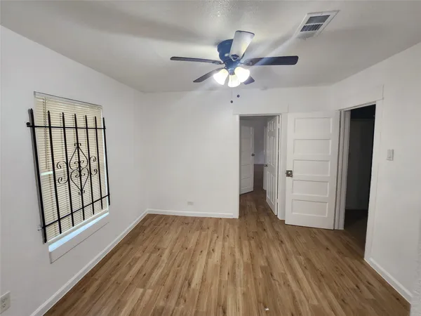 an empty room with wooden floor and windows