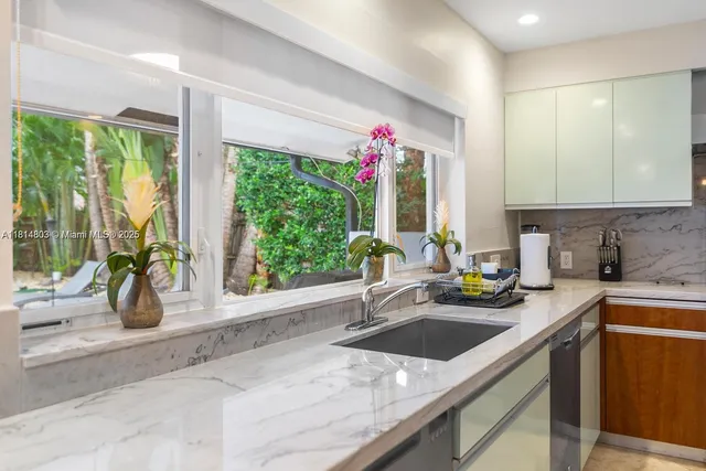 a kitchen with a sink a counter and a living room view