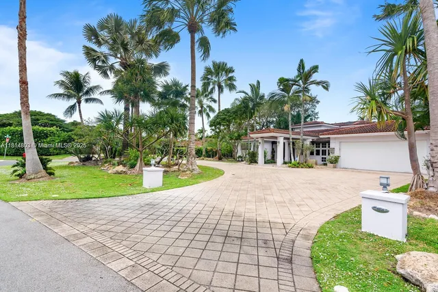 a view of a house with a yard and palm trees