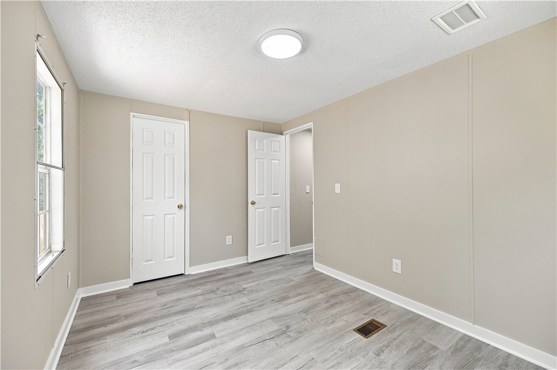 213 Old River Road Pelzer, SC 29669 - Photo 18 of 27 Smooth wood-look flooring and crisp white trim enhance this versatile bedroom space.