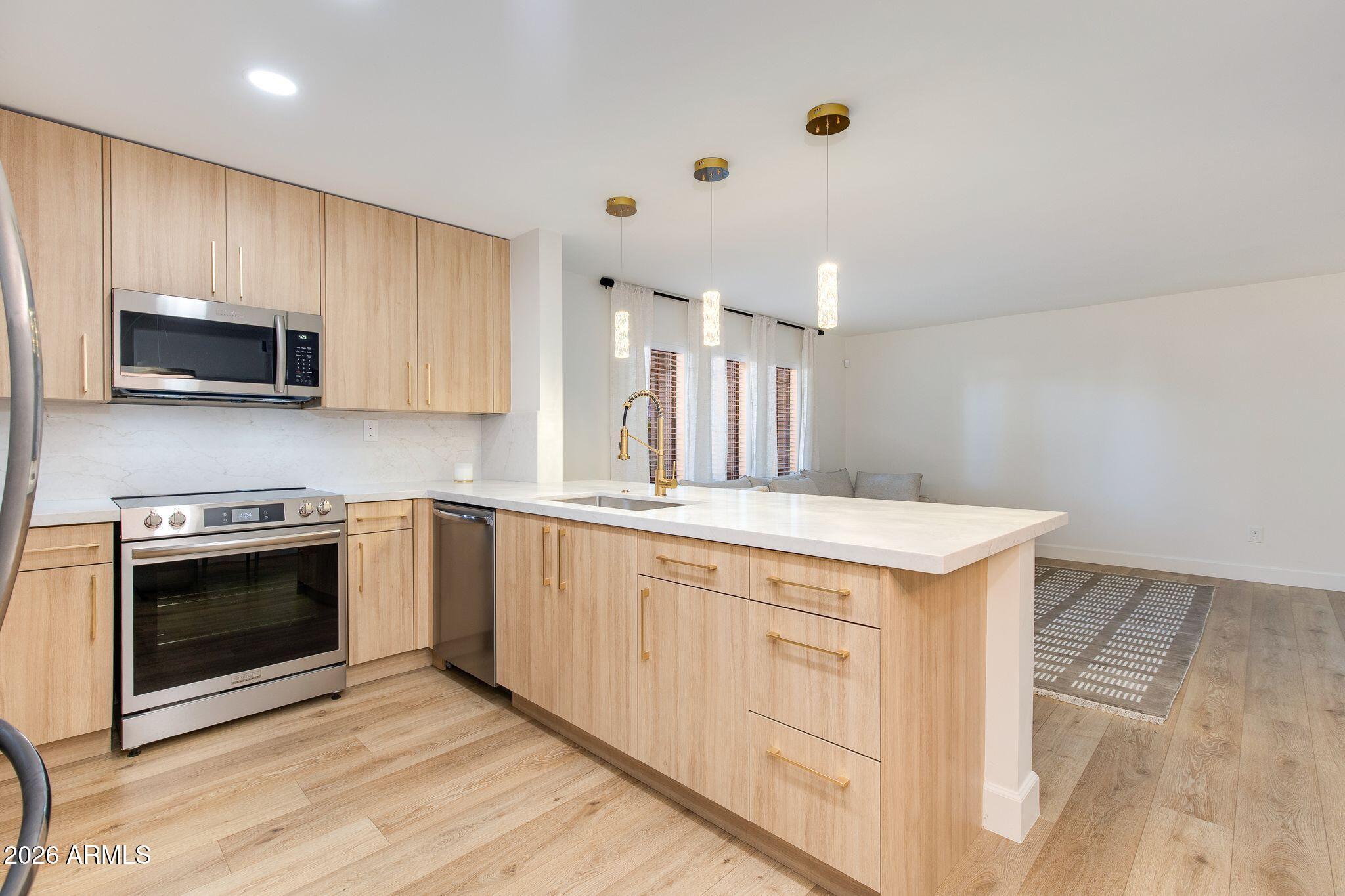 5201 North 24th Street, Unit 107 Phoenix, AZ 85016 - Photo 5 of 15 a kitchen with granite countertop a stove top oven a sink dishwasher and white cabinets with wooden floor