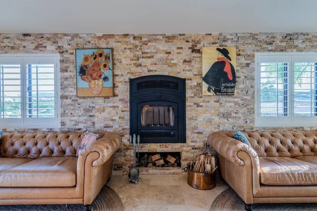 a living room with furniture large window and wooden floor