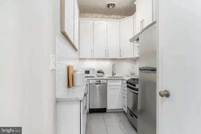 a kitchen with stainless steel appliances a white stove top oven a sink a stove and white cabinets