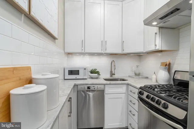 a kitchen with white cabinets and appliances