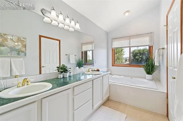 a bathroom with a granite countertop sink a large mirror a bathtub and next to a window
