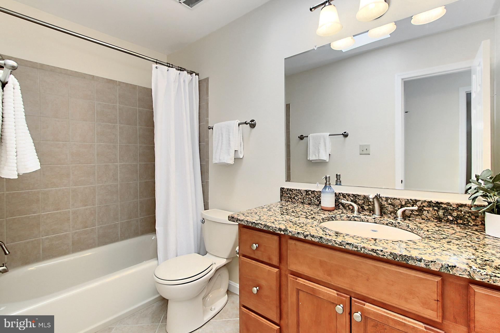 10704 Cross School Road Reston, VA 20191 - Photo 26 of 56 a bathroom with a granite countertop sink toilet and shower