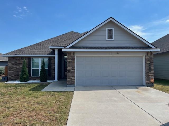 Single story home featuring brick siding, concrete driveway, a front yard, roof with shingles, and an attached garage